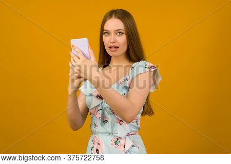 Young Woman Wears In Sunner Dress With Flowers Surprised By The News On A Smartphone - Image