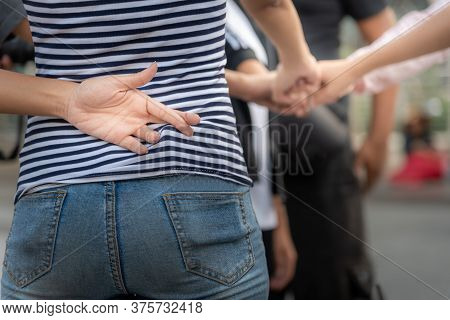 The Girl Makes Her Left Finger Cross Back, While Using The Right Hand To Do Fist Bump With Her Frien