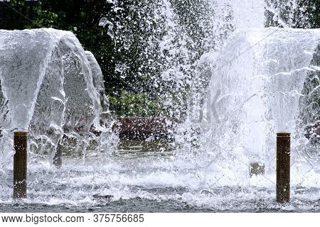 Selective Focus On Spray Of Urban Fountain And Blurred Background. A Fountain With Splashes And Drop
