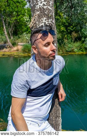 Young Man In White Pants And Modern Styling Posing In The Freshwater Pond Of Clot De La Mare De Deu 