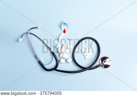 Bblue Ribbon With Stethoscope, Refined Sugar And Tablets On A Blue Background. World Diabetes Day Co
