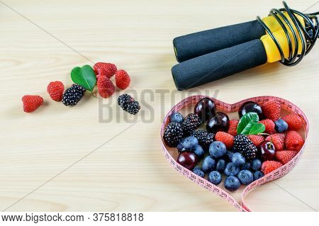 Group Of Various Berries, Dosing Tape And Jump Rope On The Light Background. Symbols Of Healthy Life