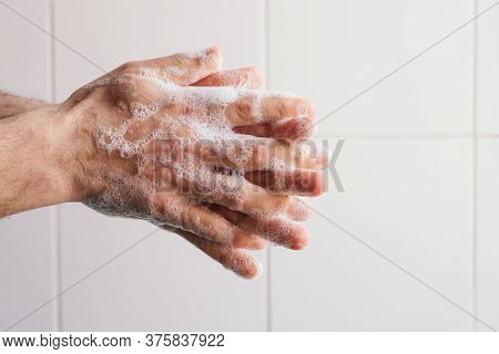 Man Cleaning His Hands Using Liquid Disinfectant Soap And Water.