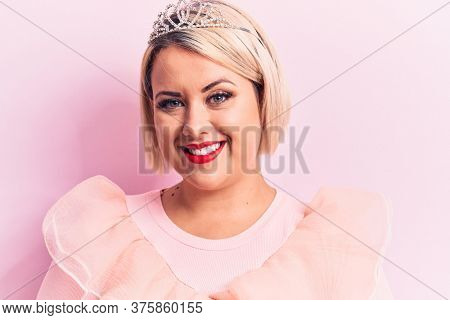 Beautiful blonde plus size woman wearing pincess tiara with diamonds over pink background with a happy and cool smile on face. Lucky person.