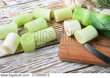 Green Chopped Leek Sultan On Choppong Board Over White Wood Table Side View.