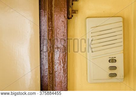 Plastic Interphone On Yellow Wall Next To A Door