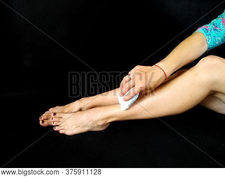 Girl In Makes Hair Removal At Home With White Epilator On Legs At Home. Isolated On Black. Selfcare 