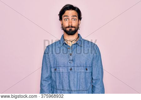 Young handsome hispanic bohemian man wearing hippie style over pink background puffing cheeks with funny face. Mouth inflated with air, crazy expression.