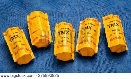 Fort Collins, CO, USA - July 10, 2020: Rolls of 120 black and white TMX (T-Max 100) film by Kodak on blue textured paper, medium format film photography concept.