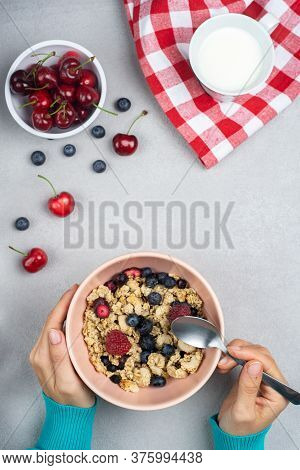 Girl Eating Breakfast And Muesli With Wooden Spoon In A Bowl With Seasonal Fruits