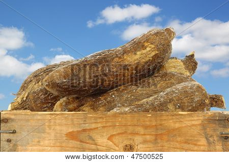 radici di manioca intero in una cassa di legno contro un cielo blu con nuvole
