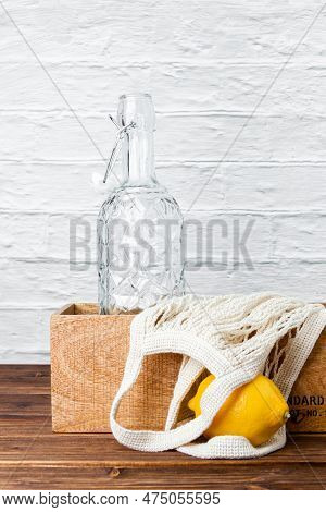 Lemonade Bottle In Crate With Lemon And Grid Bag On Wooden Table. Side View Of Fresh Citrus.