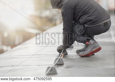 Ground Wire. A Worker Lays A Ground Cable On The Roof Of A Building. Electrician Fixing Aluminum Wir