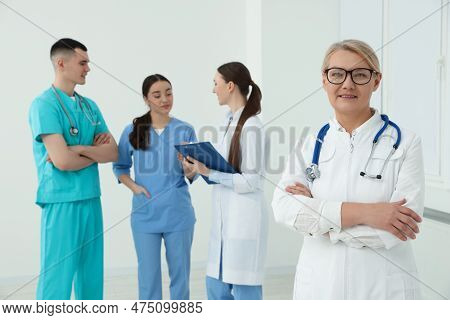 Portrait Of Doctor Near Colleagues In Clinic
