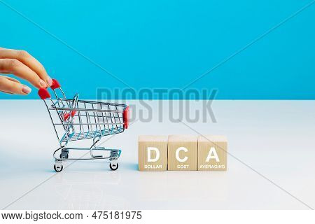 The Text Dca Is Written On Wooden Cubes And Woman's Hand Pushingn Empty Shopping Cart In Studio On B
