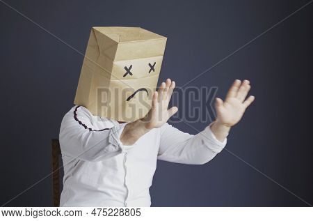 A Sad Man In A White Shirt With A Bag On His Head, With A Sad Emoticon Drawn, Is Afraid, Defends Him