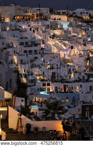 Imerovigli, Santorini, Greece - July 1, 2021: Illuminated Whitewashed Houses With Terraces And Pools