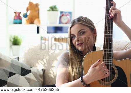 Talented Purposeful Young Woman Holds Guitar In Hands. Woman Practicing Playing Musical Chords Impro
