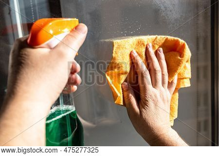 Cleaning Outdoor Home Window Glass In Urban House Close Up On Sunny Spring Day (focus On Hand With R