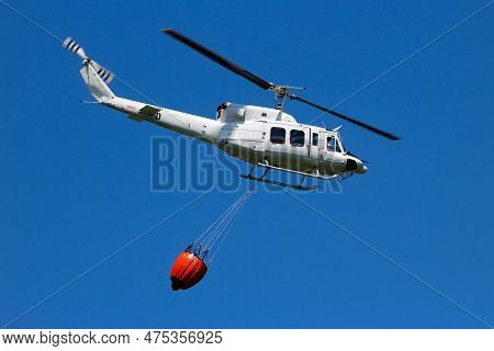 Helicopter With A Bambi Bucket Filled With Water To Fight A Forest Fire