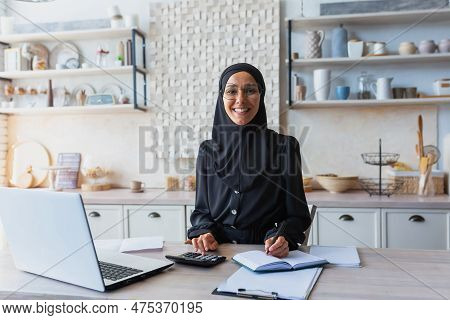 Portrait Of Young Muslim Woman In Hijab And Burqa Working As Accountant, Auditor From Home. Remotely