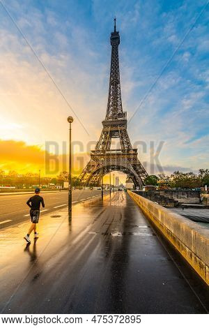 Young Man Run On The Bridge At Sunrise Time After Rain. Morning Jogging Under Eiffel Tower In Paris,