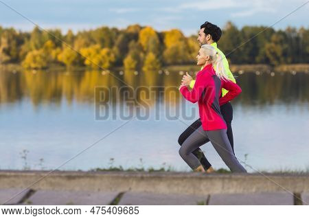 Jogging Concepts. Running Couple While Training Outdoors On Road At River For Durable Marathon Prett