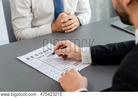Interviewing Job Applicant In Office With Resume Paper. Candidate Wear Suit For Formal Conversation 