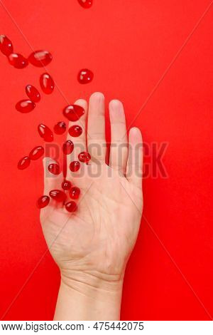 Krill Oil Capsules In A Hand On A Red Background .omega Fatty Acids.flying Gelatin Red Krill Oil Cap
