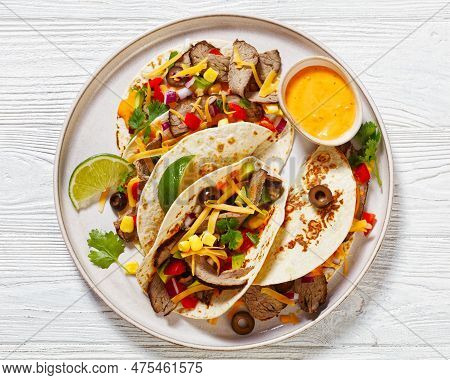 Grilled Steak Tacos With Olives, Tomatoes, Red Onion, Avocado, Cilantro, Corn, Shredded Cheddar Chee