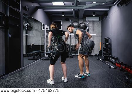 Ems Training Concept. Shot From The Back Of A Female Athlete Wearing An Ems Suit And A Male Trainer 