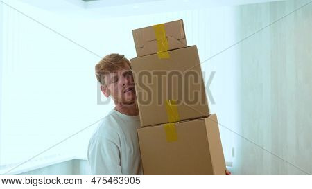 Close Up Of Handsome Caucasian Red-haired Guy Holding Many Cardboard Boxes In Hands. Boxes Falling O
