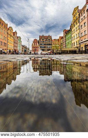 Wroclaw, Poland - July 2022: Wroclaw Market Square Old Tenement Houses Reflected In Small Puddle