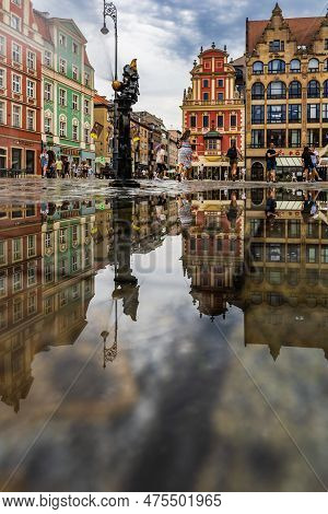 Wroclaw, Poland - July 2022: Wroclaw Market Square Old Tenement Houses Reflected In Small Puddle