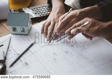 The Home Design Architects Are Reviewing The House Plan Draft, The Project Commissioned By The Clien