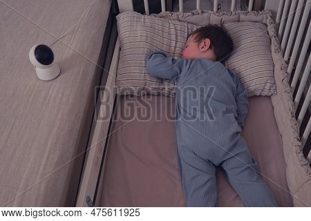 Baby Sleeps Next To The Surveillance Camera In The Nursery. Home Camera Monitors Whether The Child H