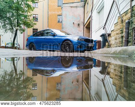 Wroclaw, Poland - August 2022: Blue Bmw Car Standing On Car Parking And Reflected In Small Puddle