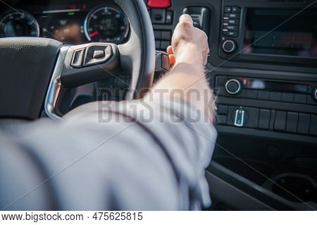 Caucasian Semi Truck Driver Behind The Wheel Transportation Industry Theme. Modern Euro Semi Tractor