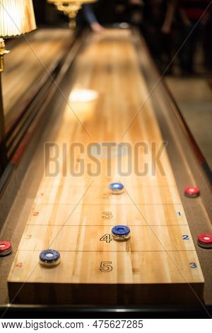Playing The Game Of Shuffleboard In A Bar.
