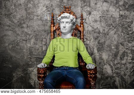 Modern Art Collage. Attractive Young Man With Gypsum Head Of Of David Sitting On The Throne