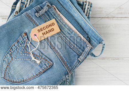Stack Of Blue Jeans And Tag With Inscription Second Hand On White Background. Second Hand Clothing S