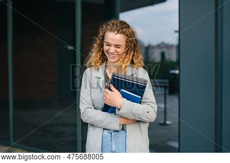 Culry-haired Woman Student Happily Holding Laptop Outdoors After School On Campus. Back To School, S