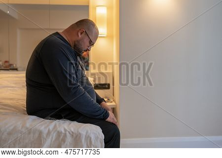 Overweight Sad Man Resting Alone In Hotel Having Midlife Crisis Sitting On Bed And Boring, Side View