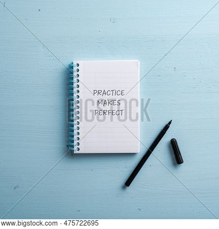 Top View Of A Spiral Notepad With Practice Makes Perfect Sign In It. With Black Marker Next To It. O