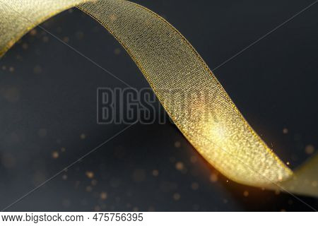 Golden Ribbon Isolated On Black Background And Texture. Gold Gift Wrap Ribbon On Black Fabric Backgr