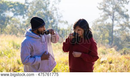 Couple Drink Coffee In Morning Time. Young Couple Holding Mugs While Enjoying The View Of Nature. \r