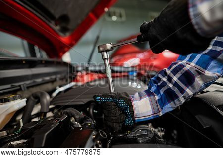 Female Auto Mechanic Unscrewing A Nut To Replace A Car Spark Plug.