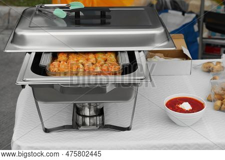 Volunteer Food Distribution. Metal Warmer With Tasty Stuffed Cabbage And Bowl Of Borsch Served On Ta
