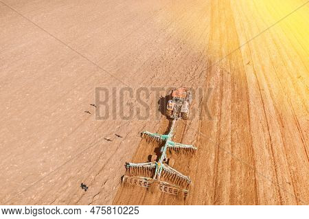 Top View Tractor Plowing Field In Spring Season. Beginning Of Agricultural Spring Season. Cultivator