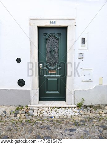 Evora, Portugal- October 10, 2022: Typical Portuguese Facade With Red Wooden Door On Cobblestone Str